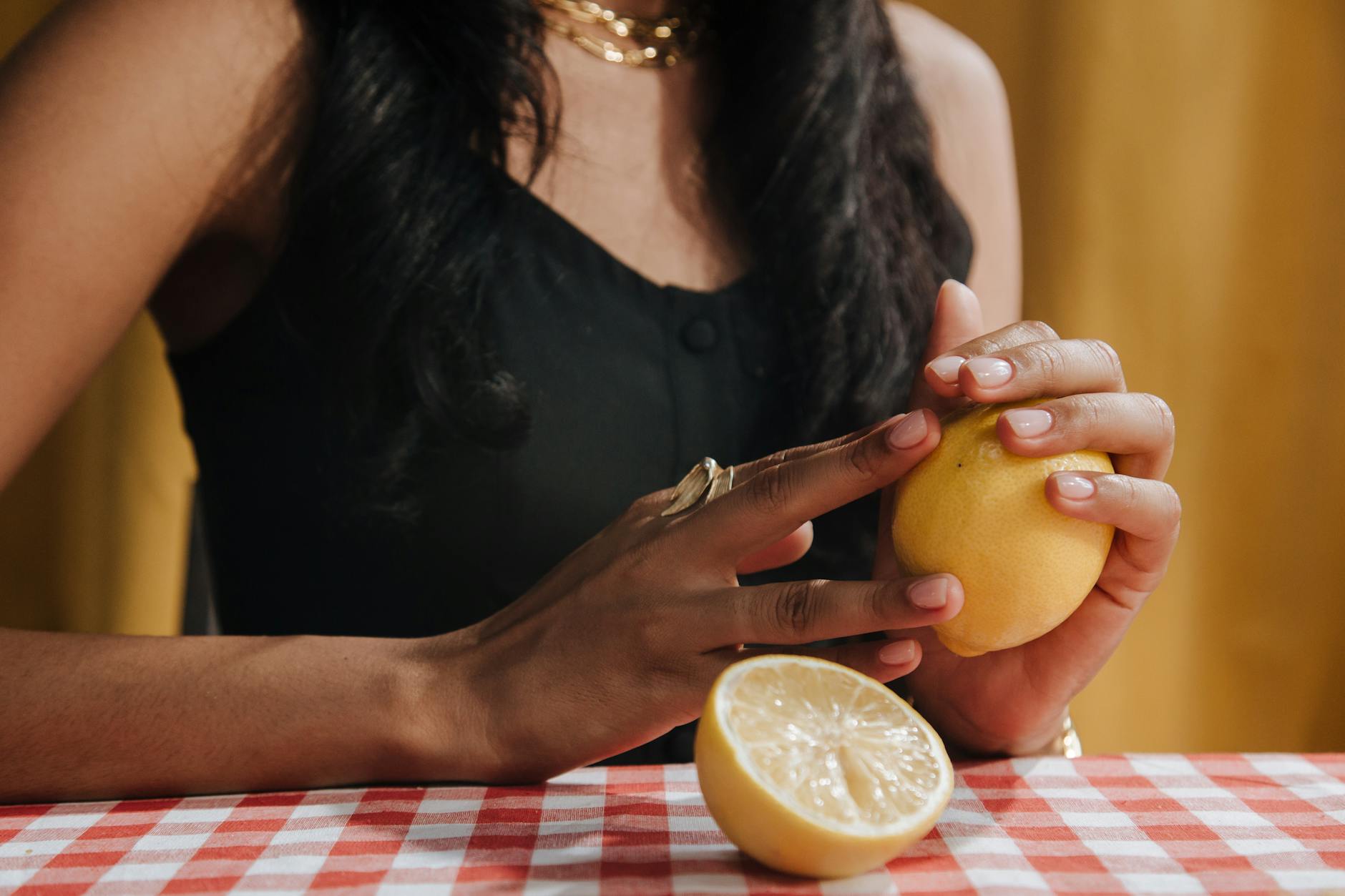 Woman holding a fresh lemon at a dining table, representing peak pleasure years in your thirties