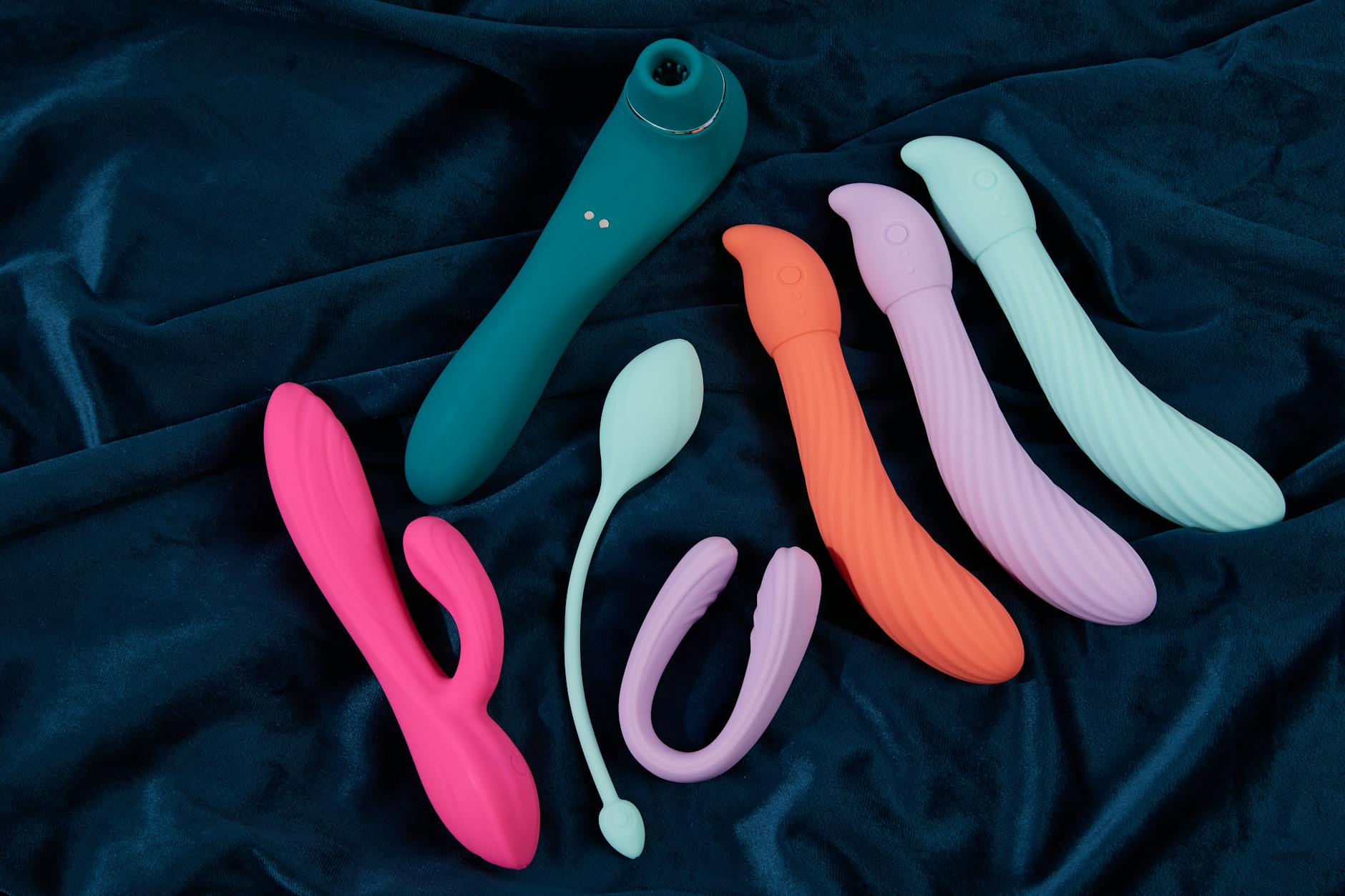 Woman holding blue and pink silicone vibrators in contemplative pose