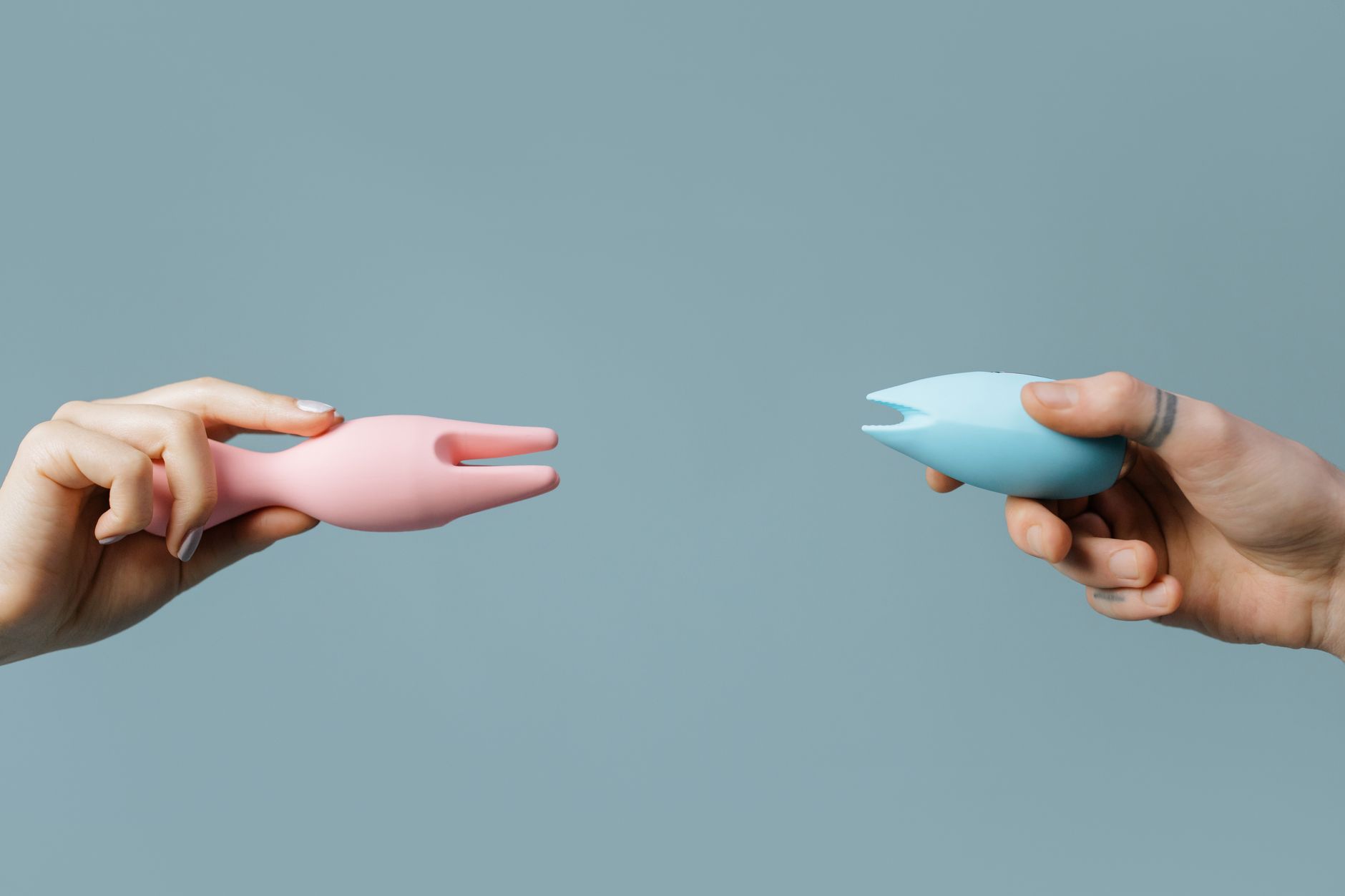 Vibrador clitoral de sucção rosa e azul contra fundo pastel.