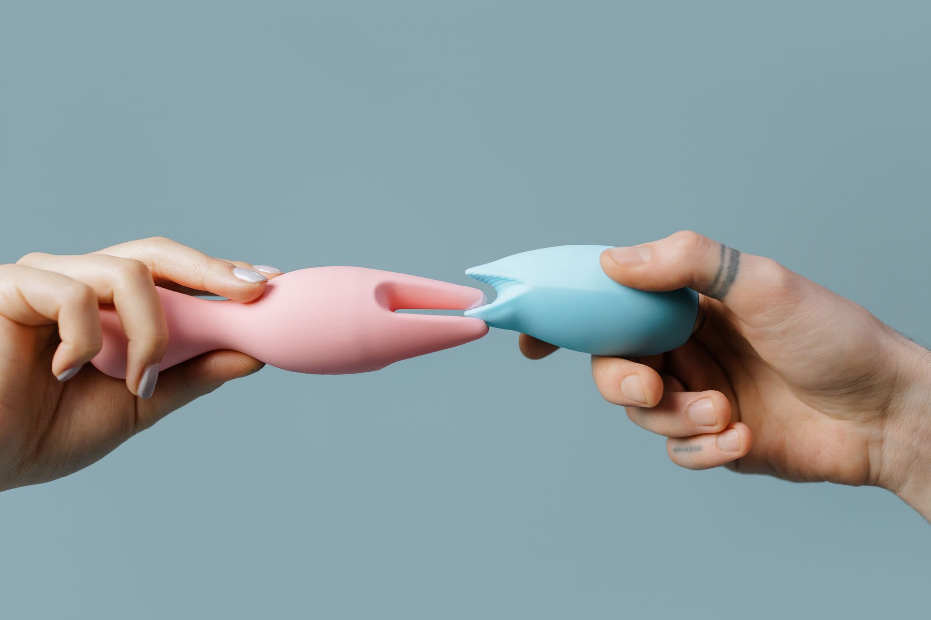 Hands holding various silicone intimate wellness toys in different colors and textures