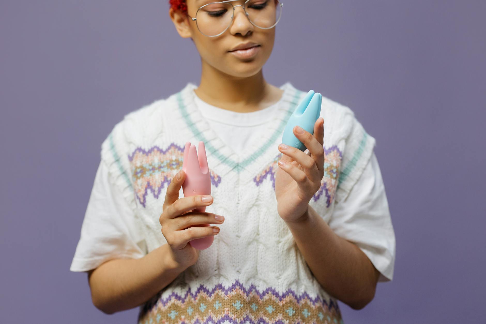 A woman holding blue and pink clitoral vibrators, representing pleasure tools for midlife bodies.